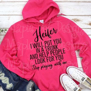 以下が含まれることがあります： 「Heifer I will put you in a trunk and help people look for you Stop playing with me」と黒で書かれたピンクのパーカー。