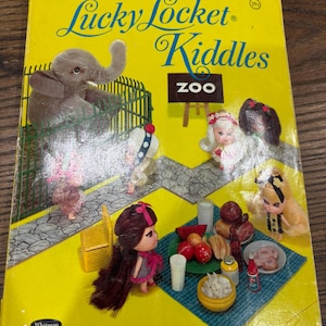 May include: Vintage "Lucky Locket Kiddles" coloring book with a yellow cover. The cover features illustrations of dolls, an elephant, and the word "ZOO". The book is a Whitman product.