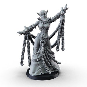 May include: A gray, detailed miniature figurine of a female elf wearing a mask and a long, flowing robe with chains. The elf is holding chains in her hands and is posed in a dancing position.