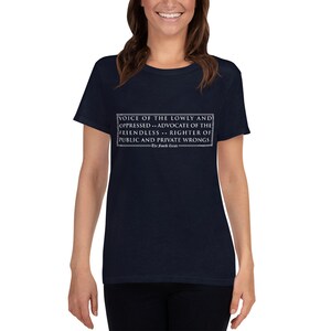 Könnte beinhalten: Ein marineblaues T-Shirt mit einem weißen Grafikdruck, der "VOICE OF THE LOWLY AND OPPRESSED... ADVOCATE OF THE FRIENDLESS... RIGHTER OF PUBLIC AND PRIVATE WRONGS." lautet. Der Text ist in einem weißen Rechteck eingeschlossen.