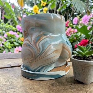 May include: A set of three ceramic mugs with a speckled, matte finish. The mugs are in shades of cream, light gray, and dark gray. Each mug has a simple, minimalist design, perfect for coffee or tea.