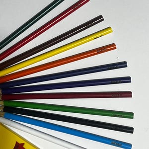 Puede incluir: Un conjunto de l&aacute;pices de colores en varios colores, incluyendo verde, rojo, marr&oacute;n, amarillo, naranja, azul y blanco. Cada l&aacute;piz est&aacute; etiquetado con el nombre "BRYAN". Los l&aacute;pices est&aacute;n abanicados, con una caja parcialmente visible en la esquina inferior izquierda.
