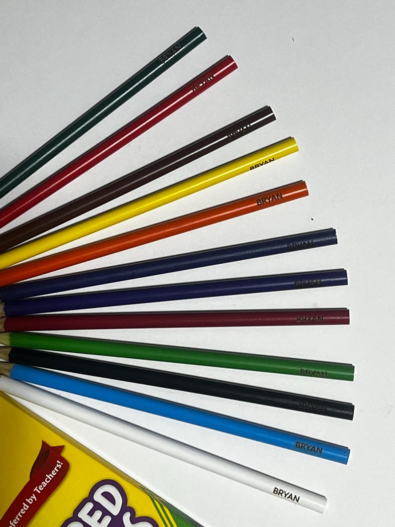 Puede incluir: Un conjunto de l&aacute;pices de colores en varios colores, incluyendo verde, rojo, marr&oacute;n, amarillo, naranja, azul y blanco. Cada l&aacute;piz est&aacute; etiquetado con el nombre "BRYAN". Los l&aacute;pices est&aacute;n abanicados, con una caja parcialmente visible en la esquina inferior izquierda.