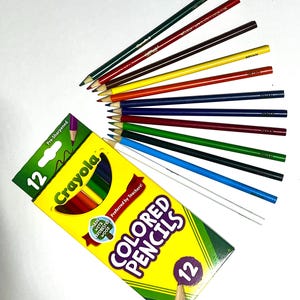 Puede incluir: Una caja de 12 l&aacute;pices de colores Crayola con el texto "COLORED PENCILS" y "12" en la caja. Los l&aacute;pices est&aacute;n dispuestos en forma de abanico, mostrando varios colores, incluyendo verde, rojo, amarillo y azul. La caja tambi&eacute;n dice "Preferred by Teachers!"