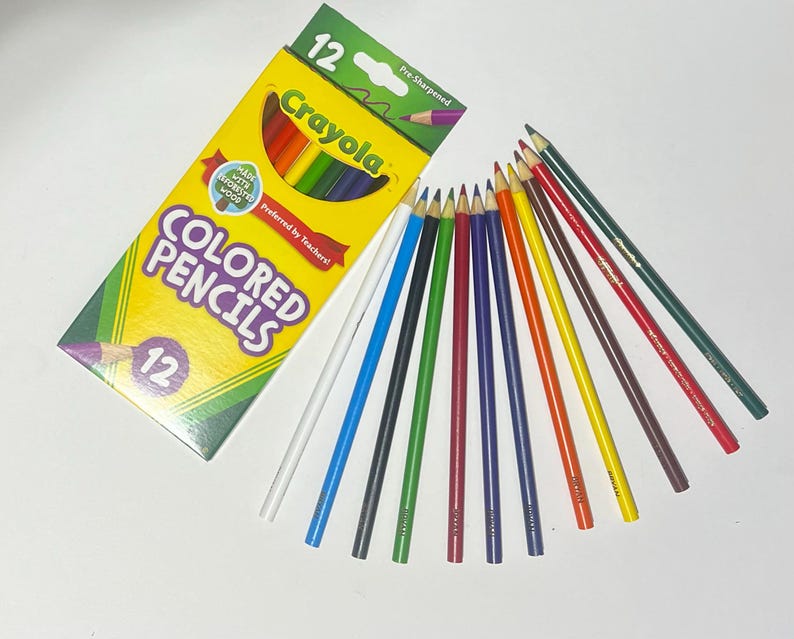 Puede incluir: Una caja amarilla y verde de 12 l&aacute;pices de colores Crayola preafilados, con las palabras "COLORED PENCILS" y "Crayola" impresas en la caja. Los l&aacute;pices est&aacute;n dispuestos en forma de abanico, mostrando una variedad de colores.