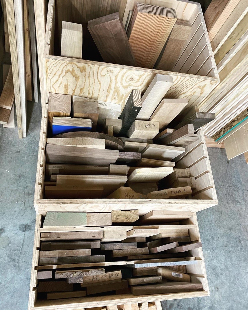 Puede incluir: Una caja de almacenamiento de madera con m&uacute;ltiples compartimentos llenos de varios tipos de madera. La caja est&aacute; etiquetada con los nombres de los diferentes tipos de madera, como "Maple" y "Walnut".
