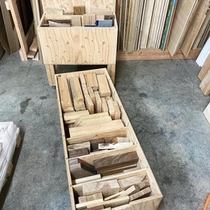 Puede incluir: Una caja de madera llena de diferentes tipos de restos de madera, organizados en filas. La caja est&aacute; hecha de madera contrachapada y tiene un acabado de madera natural.