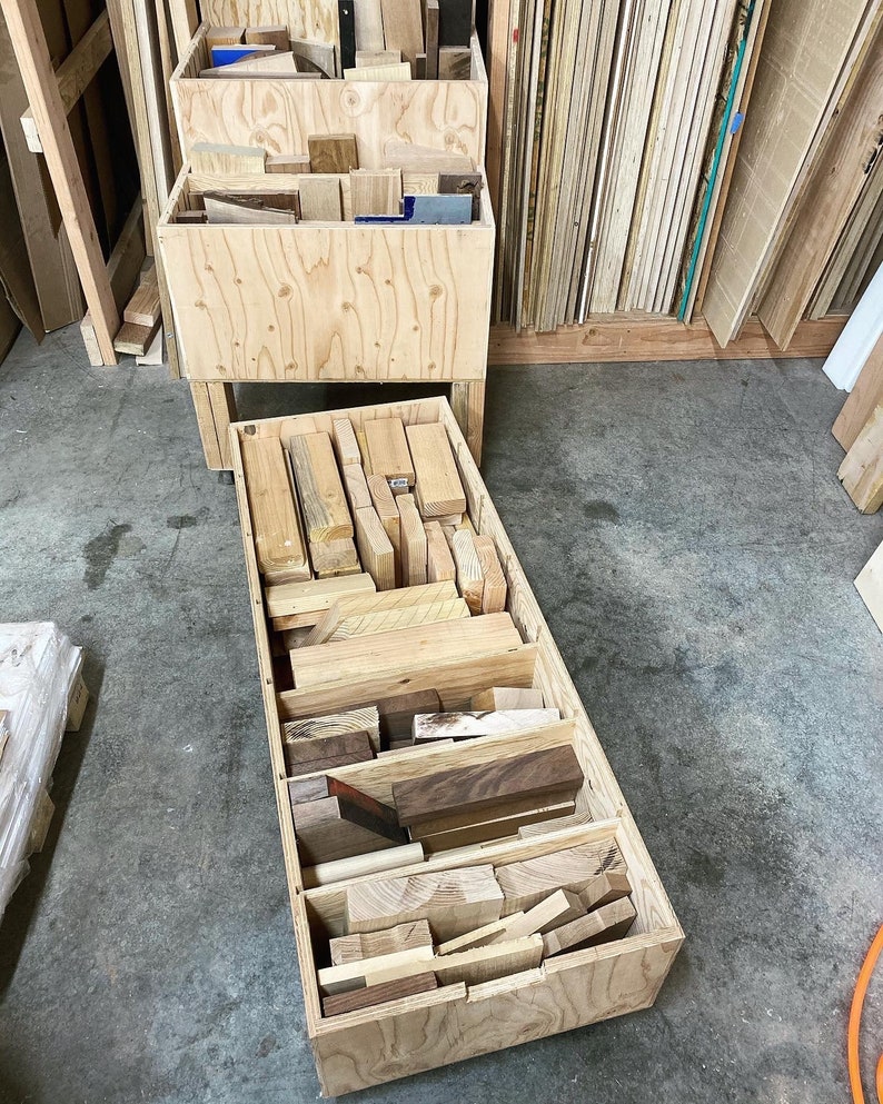 Puede incluir: Una caja de madera llena de diferentes tipos de restos de madera, organizados en filas. La caja est&aacute; hecha de madera contrachapada y tiene un acabado de madera natural.