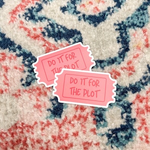 May include: Two pink stickers with the text "Do it for the plot" in white lettering. The stickers are on a patterned surface.