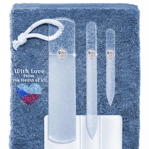 May include: A set of four glass nail files in a blue towel pouch. The files are clear and have a rounded shape. The pouch has a white drawstring and the text "With Love from the Heart of EU" is printed on the front.