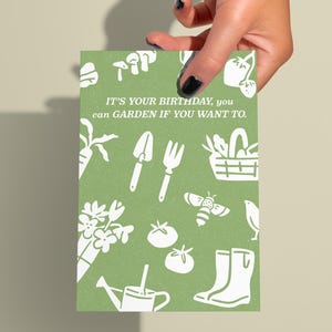 Puede incluir: Tarjeta verde con ilustraciones blancas de herramientas de jardinería, plantas y una abeja. El texto dice "IT'S YOUR BIRTHDAY, you can GARDEN IF YOU WANT TO."
