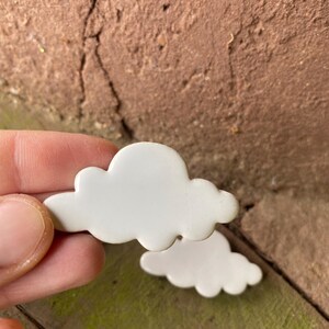 May include: A set of three white ceramic cloud shapes. The clouds are smooth and have a slightly rounded shape.