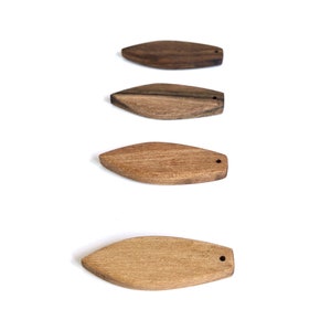 Pode incluir: Quatro ornamentos de madeira em forma oval com um furo no topo. Os ornamentos estão dispostos verticalmente, com o maior na parte inferior e o menor na parte superior. Os ornamentos são feitos de madeira marrom de diferentes tons.