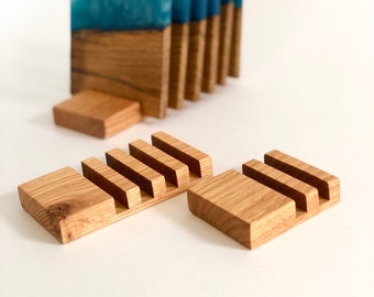 Puede incluir: Conjunto de seis posavasos de madera con tapas de resina azul. Los posavasos están apilados en un soporte de madera.