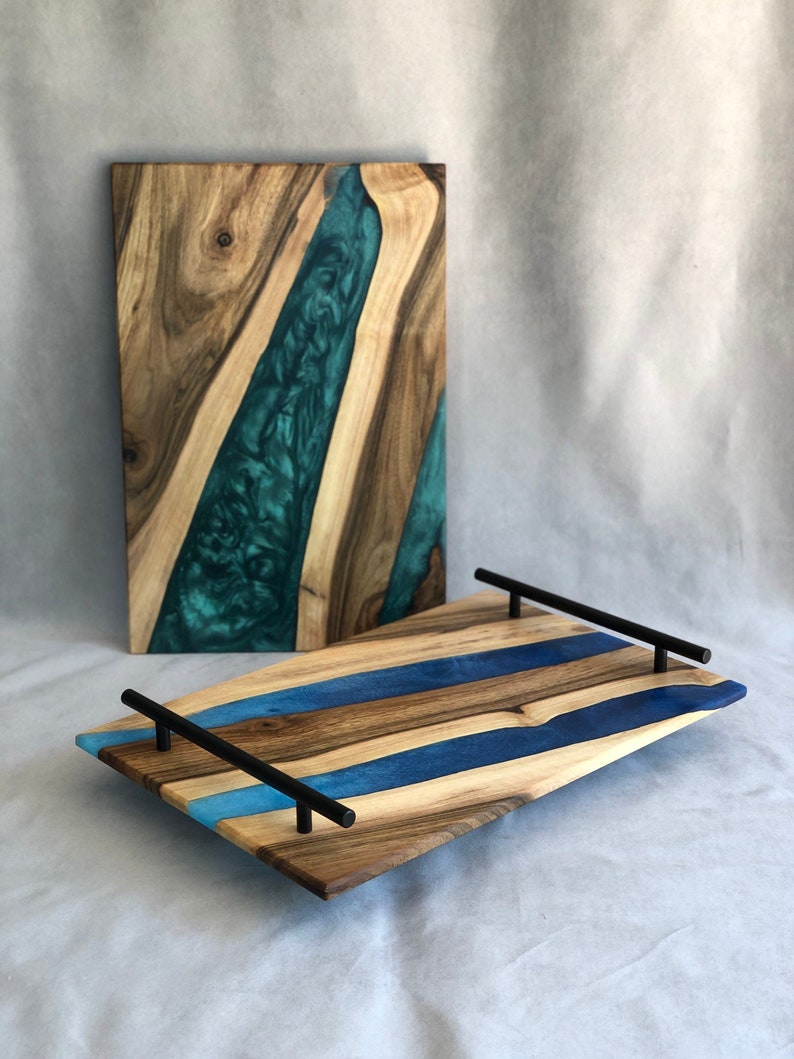 May include: A rectangular serving tray made of wood with blue and brown resin inlay. The tray has two black metal handles.
