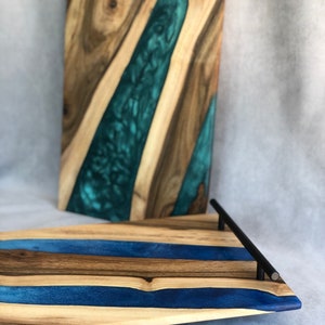 May include: A wooden serving tray with a blue and brown epoxy resin design. The tray has a black metal handle.