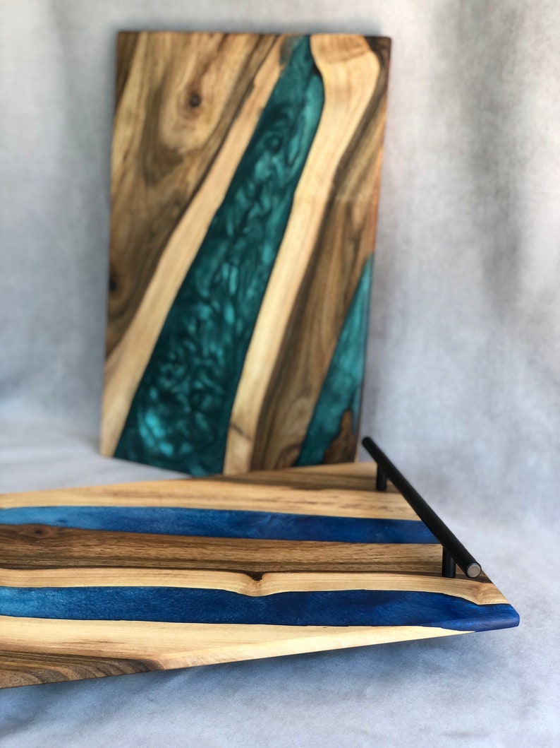 May include: A wooden serving tray with a blue and brown epoxy resin design. The tray has a black metal handle.