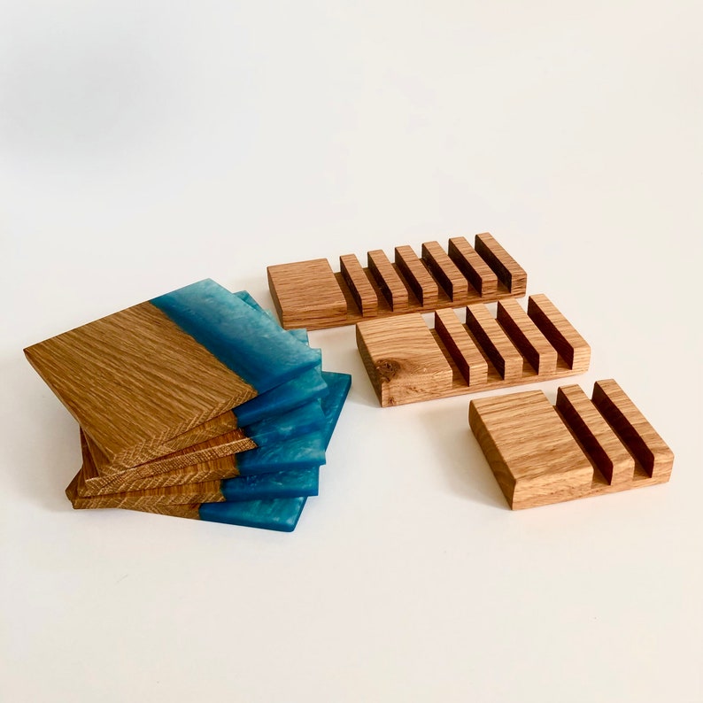 Puede incluir: Un juego de seis posavasos de madera con una incrustaci&oacute;n de resina azul. Los posavasos est&aacute;n apilados uno encima del otro. Tambi&eacute;n hay tres soportes de posavasos de madera con ranuras para los posavasos.