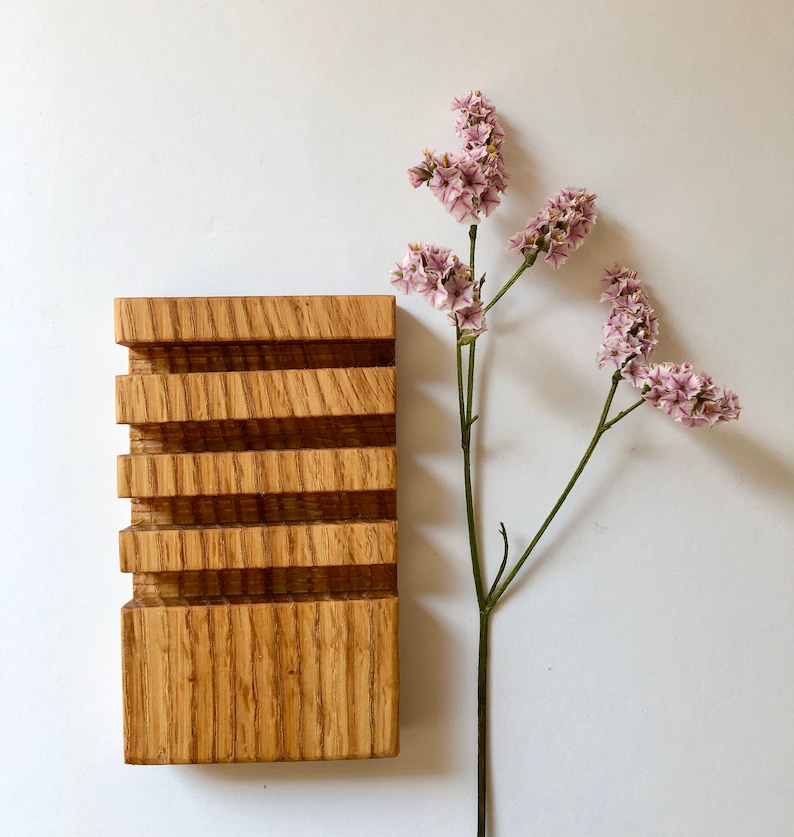 Puede incluir: Un jabonera de madera con cinco compartimentos, hecha de madera marr&oacute;n claro con un patr&oacute;n de veta natural. La jabonera est&aacute; sobre una superficie blanca.