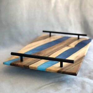 May include: A wooden serving tray with blue and light blue resin inlay and black metal handles.