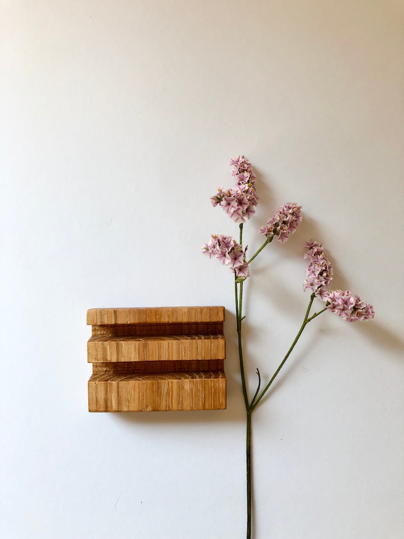Puede incluir: Un jabonera de madera con tres compartimentos, hecha de madera marr&oacute;n claro. Una rama de flores rosas con p&eacute;talos delicados se encuentra en el lado derecho de la imagen.