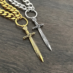 May include: Two gold and silver chains with sword pendants. The chains are curb style and the swords have intricate designs.