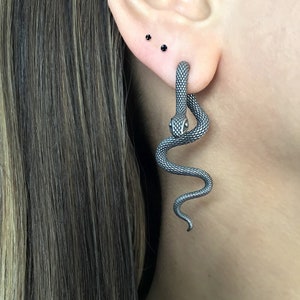 Op de afbeelding: Een zilveren slangen oorring met een gedetailleerd ontwerp. De slang is opgerold en heeft een realistisch uiterlijk.