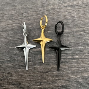May include: Three star-shaped hoop earrings in silver, gold, and black.