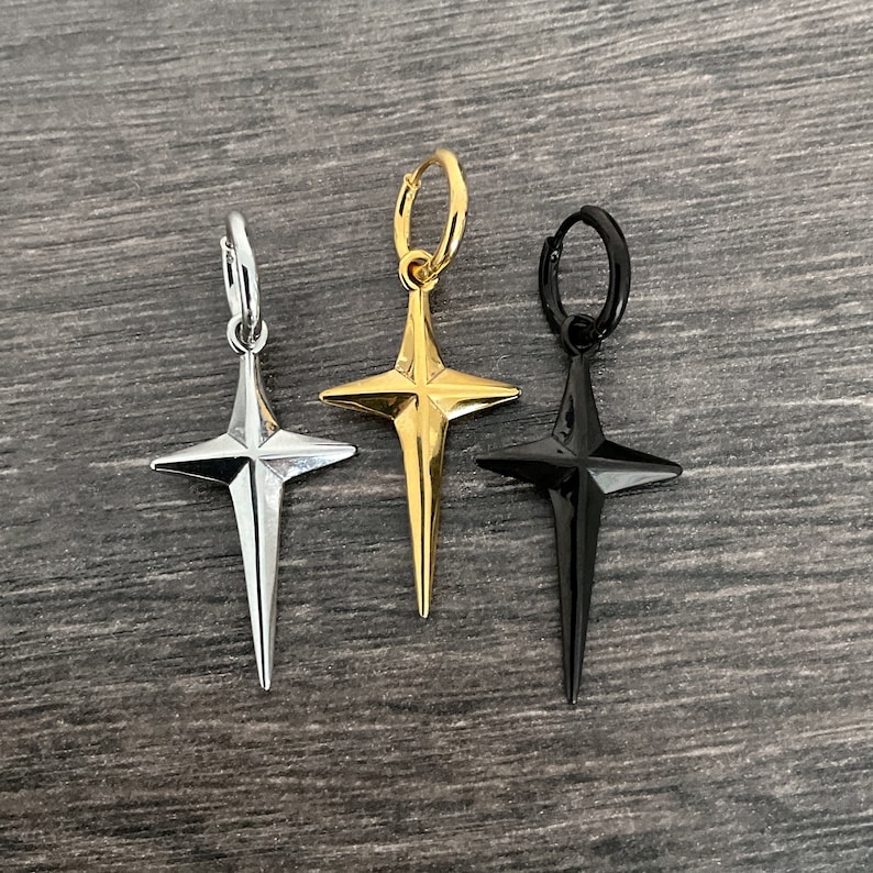 May include: Three star-shaped hoop earrings in silver, gold, and black.