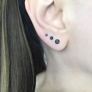 May include: Three black diamond stud earrings of different sizes. The earrings are set in silver.