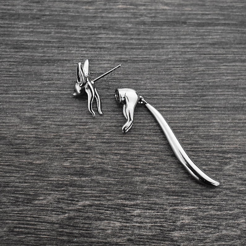 May include: Silver dangle earrings with a butterfly design. The earrings are made of two pieces, a butterfly stud and a long, curved dangle.