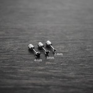May include: Three silver stud earrings with black gemstones, lined up from largest to smallest. The earrings are labeled 4mm, 3mm, and 2mm.
