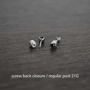 May include: A pair of black gemstone earrings with screw back closures. The earrings have a silver post and a 21 gauge thickness.
