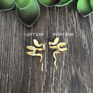 Puede incluir: Un par de pendientes de serpiente de oro. Los pendientes est&aacute;n dise&ntilde;ados para envolverse alrededor de la oreja y tienen un dise&ntilde;o de serpiente. El texto "LEFT EAR" y "RIGHT EAR" est&aacute; impreso en la superficie de madera.