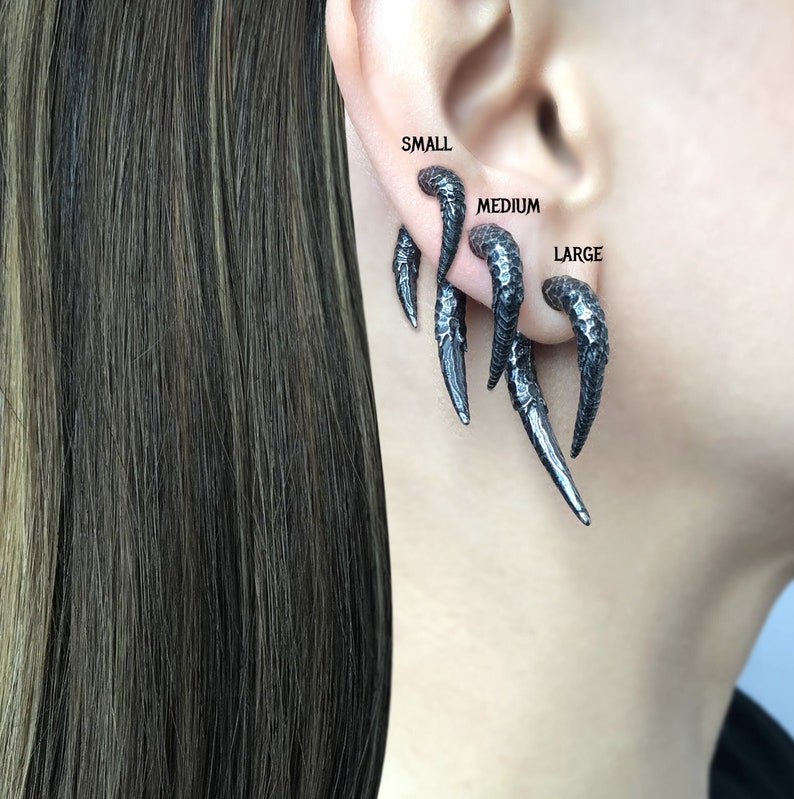Peut inclure: Trois boucles d'oreilles en m&eacute;tal noir de diff&eacute;rentes tailles, &eacute;tiquet&eacute;es "petite", "moyenne" et "grande".