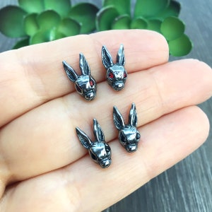 May include: Four silver rabbit head stud earrings. Two have red eyes and two have black eyes.