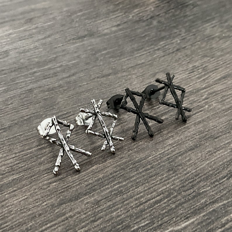 以下が含まれることがあります： 幾何学模様の銀と黒のイヤリング4つ。イヤリングは、テクスチャ加工された表面を持つ十字架の形をしています。