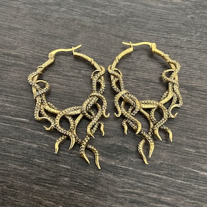 May include: A pair of gold-toned hoop earrings with an octopus design. The earrings are large and have a dangling design.