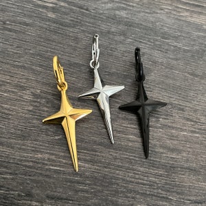 May include: Three star-shaped cross earrings in gold, silver, and black.