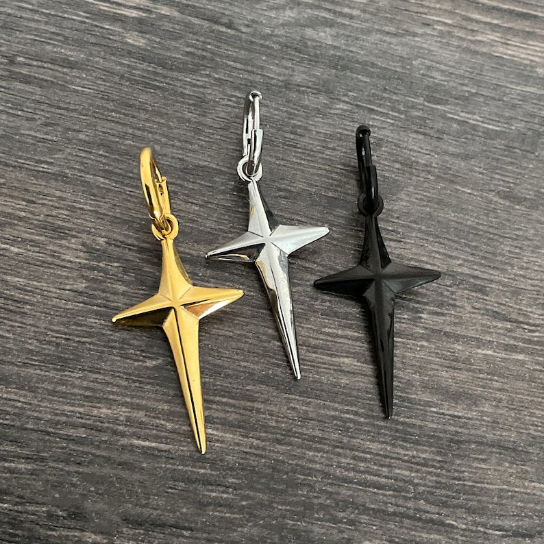 May include: Three star-shaped cross earrings in gold, silver, and black.
