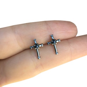 May include: A pair of silver cross stud earrings with black gemstones in the center of each cross.