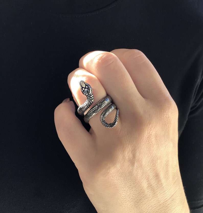 May include: A silver snake ring with a detailed design. The snake is coiled around the ring band.