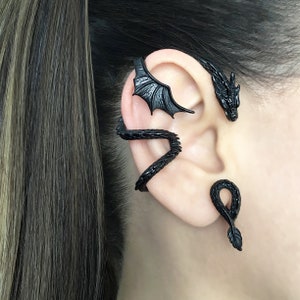 Puede incluir: Joyer&iacute;a de aro de oreja de drag&oacute;n negro. El aro se envuelve alrededor de la oreja y presenta una cabeza de drag&oacute;n y alas.