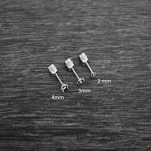 May include: Three silver stud earrings with a clear stone in the center. The earrings are 2 mm, 3 mm, and 4 mm in size.
