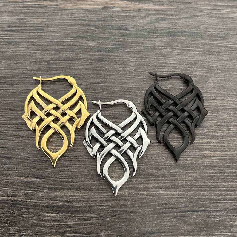 May include: Three pairs of dangle earrings with a Celtic knot design. The earrings are available in gold, silver, and black.