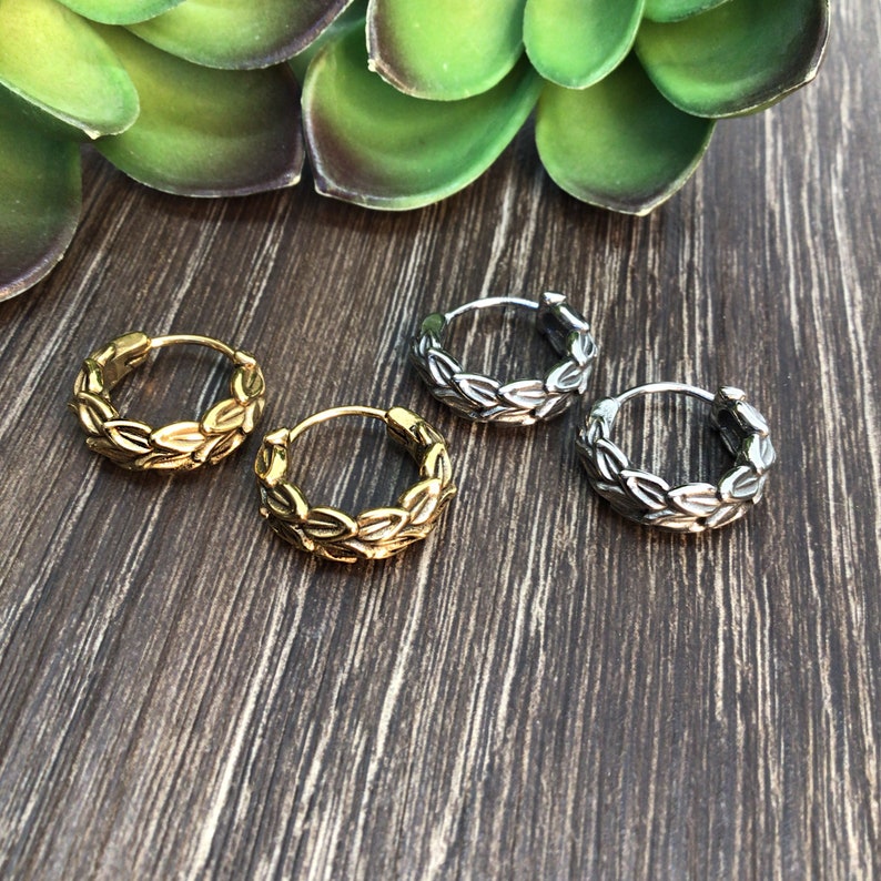 Puede incluir: Tres pares de pendientes de aro con dise&ntilde;o de hojas. Un par es dorado, uno es plateado y uno es plateado m&aacute;s oscuro.