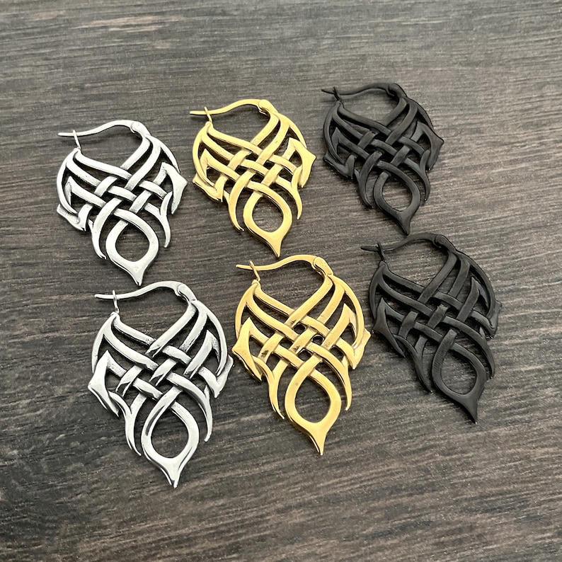 May include: Three pairs of dangle earrings with a Celtic knot design. The earrings are available in silver, gold, and black.