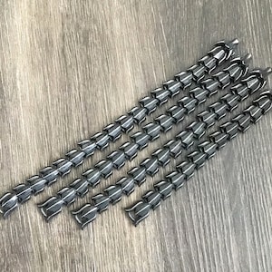 Puede incluir: Cinco cadenas de metal negro con un dise&ntilde;o de eslab&oacute;n &uacute;nico. Cada cadena tiene una serie de eslabones conectados, puntiagudos y en forma de l&aacute;grima.