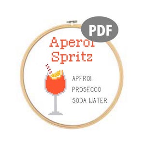 Könnte beinhalten: Ein Kreuzstichmuster für einen Aperol Spritz, mit einem Glas des Cocktails mit einer Orangenscheibe und einem Strohhalm. Der Text lautet "Aperol Spritz" und listet die Zutaten auf: Aperol, Prosecco und Sodawasser.