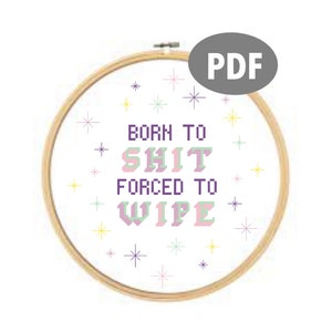 May include: A white embroidery hoop with a cross-stitch design that reads "Born to Shit Forced to Wipe". The design is in purple, pink, and green with a white background. The hoop is surrounded by a scattering of small stars in various colors.